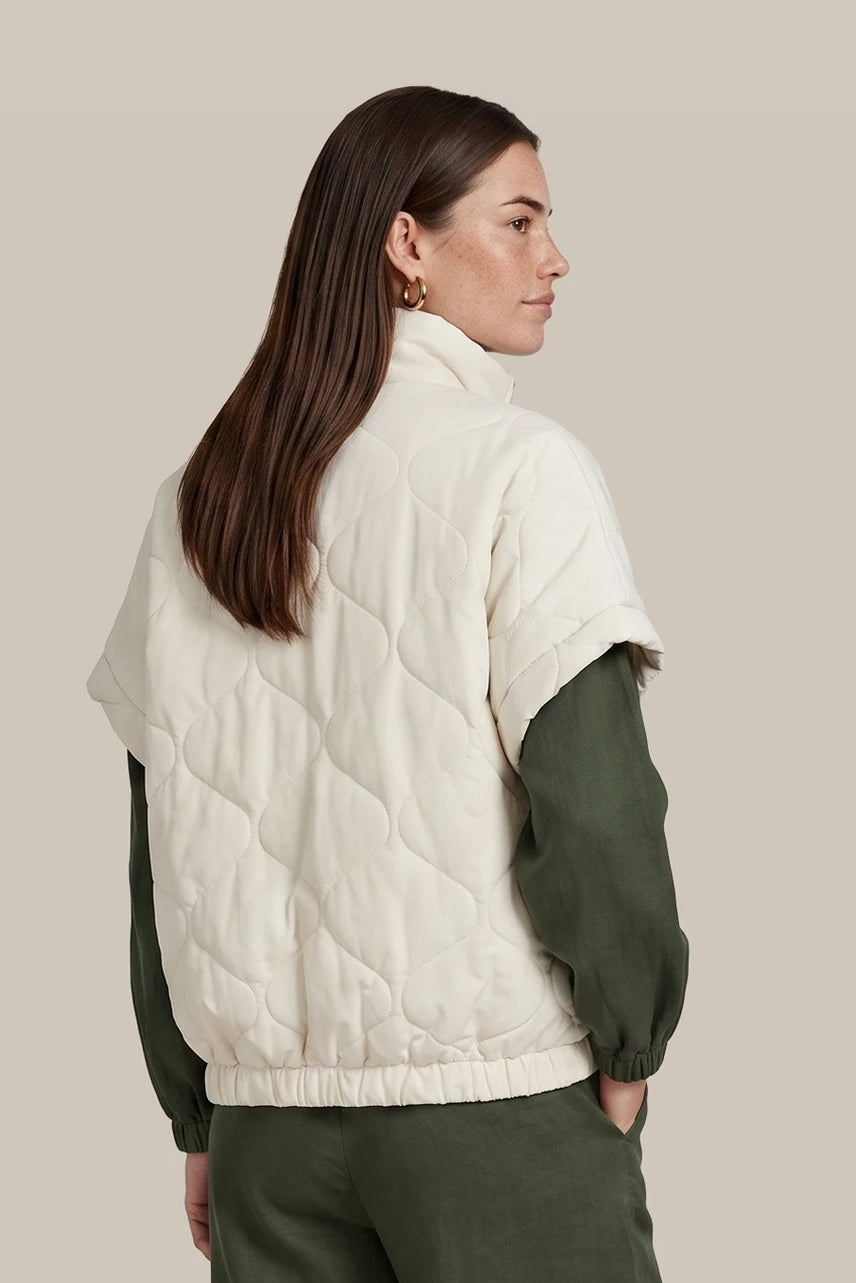 Front: “CS the Label cream quilted vest on a woman, front view with stand collar, zip front, and front pockets”