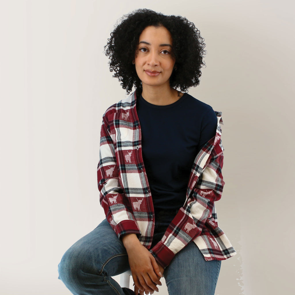 Old Ranch Organic Cotton Plaid/Cow Blouse front view: burgundy and cream plaid with highland cow print, spread collar and dark buttons, worn open over a navy top with jeans