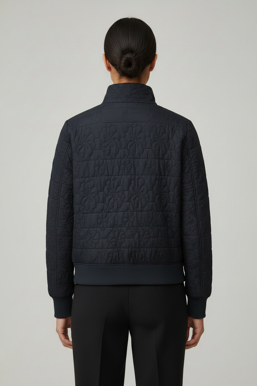 CS the Label navy quilted floral jacket on a woman, front view with high collar, gold-tone buckle, blue accent, and ribbed trim.