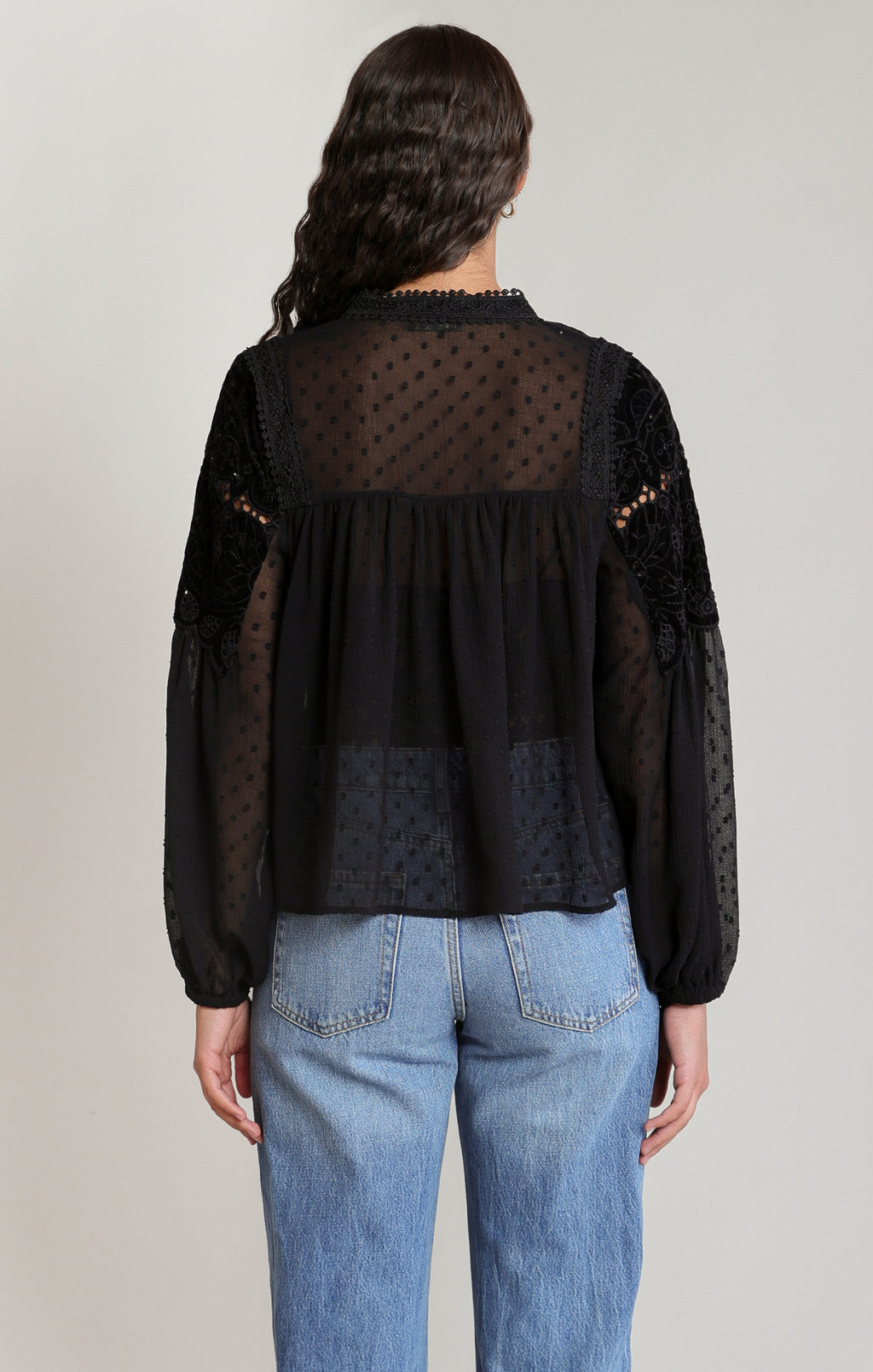 Dex sheer blouse with a tie neckline, lace and velvet detailing across the upper front, and long gathered sleeves, styled with blue jeans